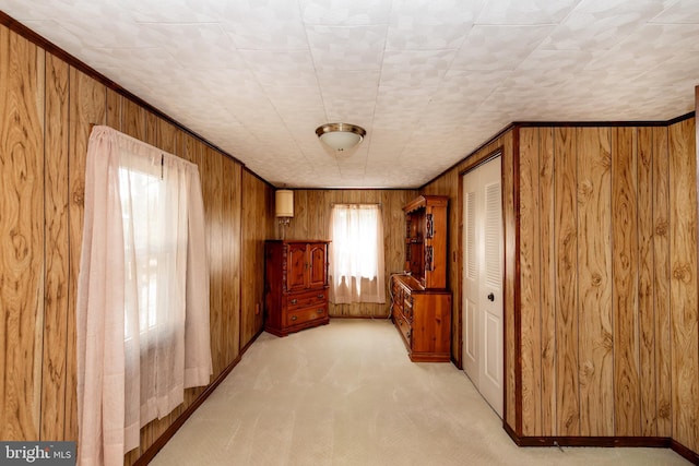 unfurnished room featuring light colored carpet, ornamental molding, and wooden walls