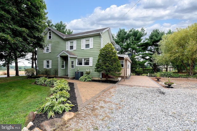 view of front of home with cooling unit and a front yard