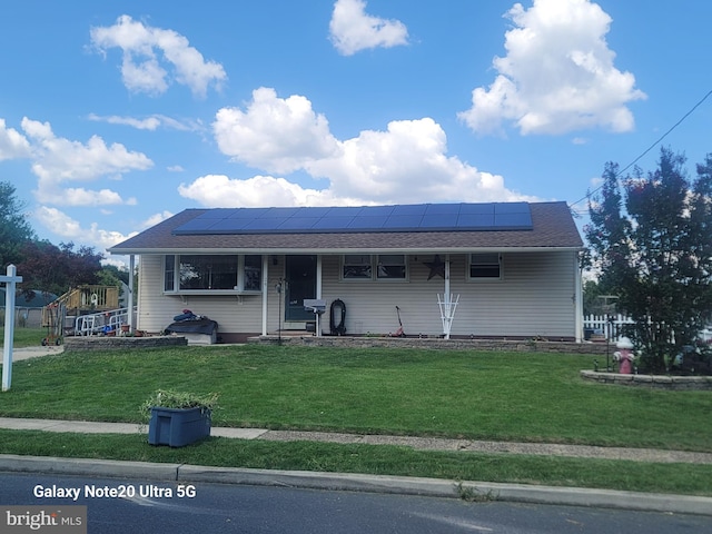 view of front of property with a front yard and solar panels