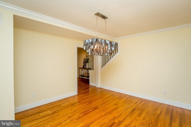 unfurnished dining area with an inviting chandelier, crown molding, and hardwood / wood-style floors