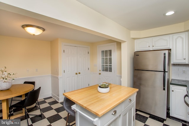 kitchen featuring decorative backsplash, white cabinetry, and stainless steel refrigerator