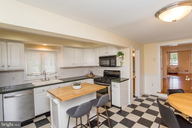 kitchen featuring a center island, sink, white cabinetry, appliances with stainless steel finishes, and a kitchen breakfast bar