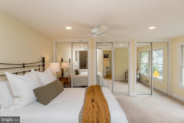 carpeted bedroom featuring ceiling fan and two closets