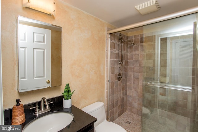 bathroom featuring a shower with shower door, toilet, and vanity