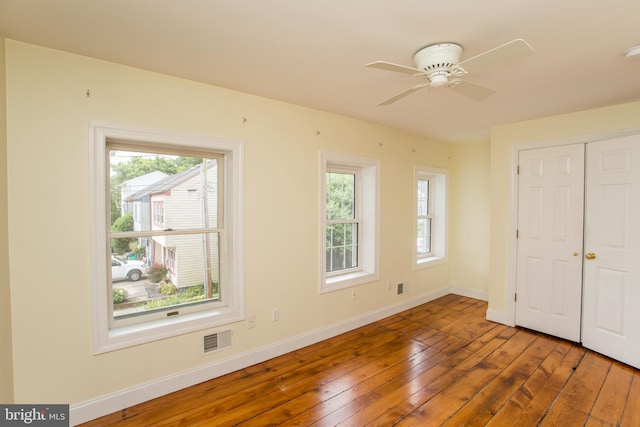 unfurnished bedroom featuring ceiling fan, a closet, and hardwood / wood-style flooring