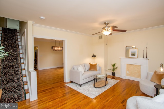 living room featuring crown molding, ceiling fan with notable chandelier, and hardwood / wood-style floors