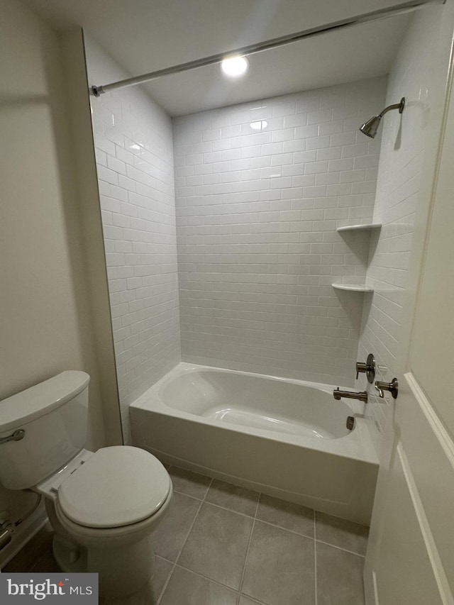 bathroom featuring toilet, tiled shower / bath, and tile patterned flooring