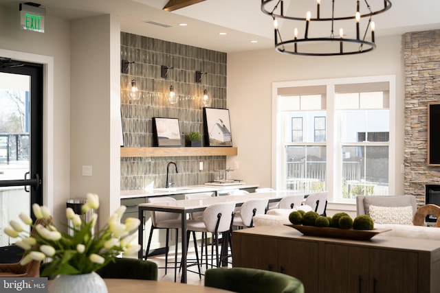 bar with sink, backsplash, and an inviting chandelier