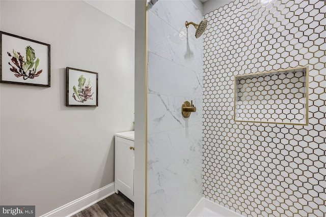 bathroom with a tile shower and hardwood / wood-style floors