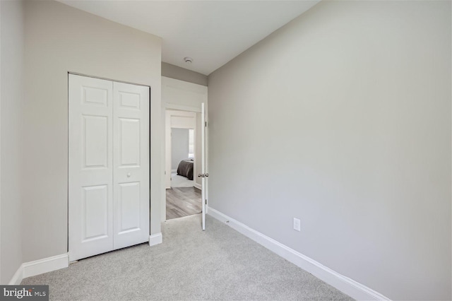 unfurnished bedroom featuring light colored carpet and a closet