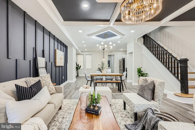 living room featuring a chandelier, light hardwood / wood-style floors, ornamental molding, and coffered ceiling