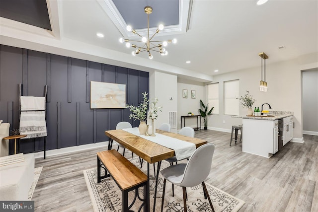 dining room with light wood-type flooring, a tray ceiling, an inviting chandelier, and crown molding