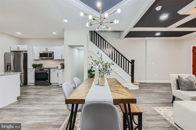 dining space featuring a chandelier, beamed ceiling, light wood-type flooring, and ornamental molding