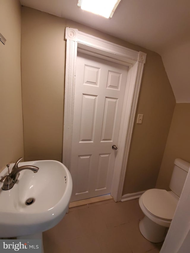 bathroom featuring lofted ceiling, tile patterned floors, toilet, and sink