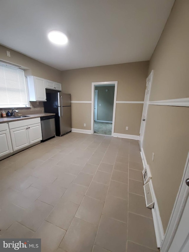 kitchen with white cabinetry, light tile patterned flooring, stainless steel appliances, decorative backsplash, and sink