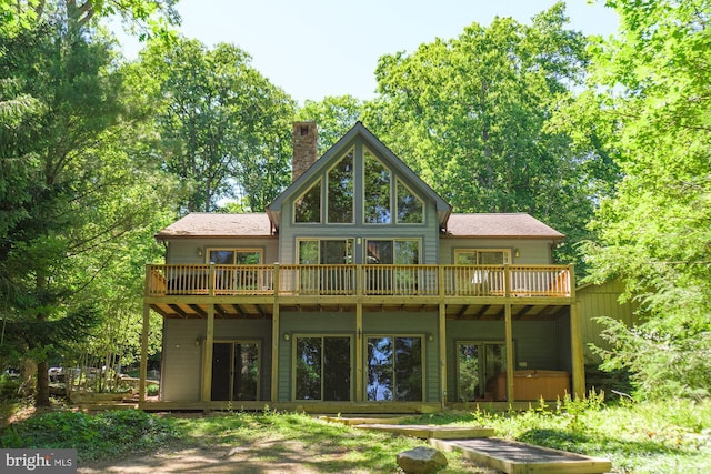 rear view of house featuring a wooden deck and a jacuzzi