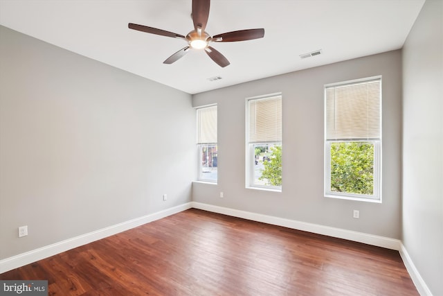 empty room featuring ceiling fan, plenty of natural light, and dark hardwood / wood-style floors