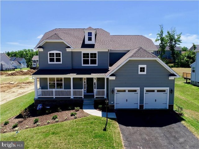 view of front of house featuring a porch, a garage, and a front yard