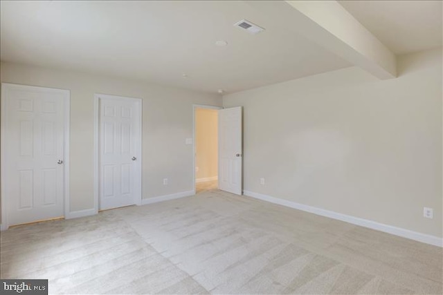 unfurnished bedroom featuring light carpet and beam ceiling