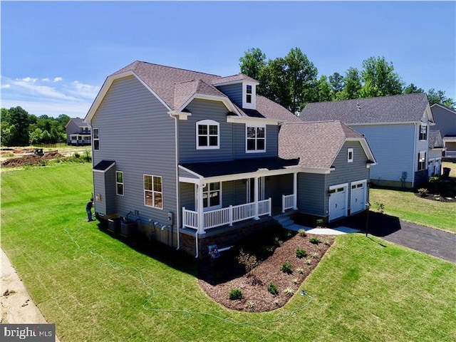 view of front of home with covered porch, a garage, and a front lawn