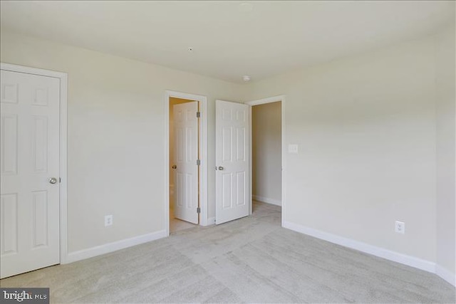 unfurnished bedroom with light colored carpet and connected bathroom