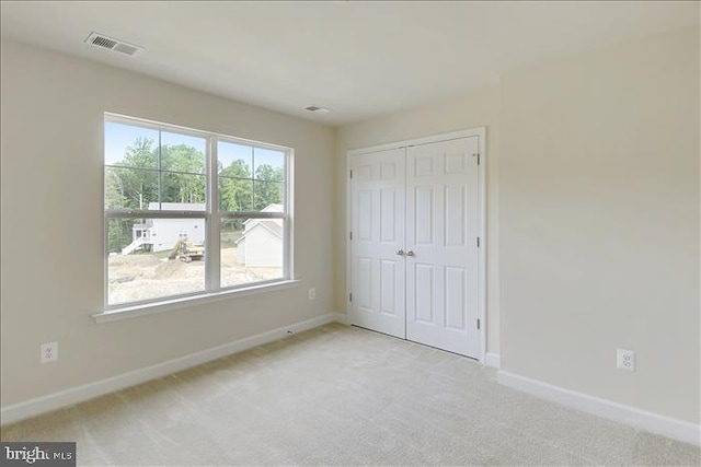 unfurnished bedroom with a closet and light colored carpet