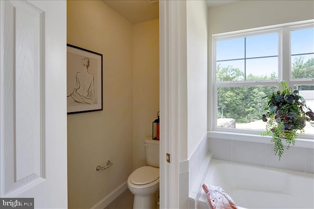 bathroom featuring a bathing tub, a healthy amount of sunlight, and toilet