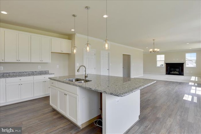 kitchen with white cabinets, sink, an island with sink, and hanging light fixtures