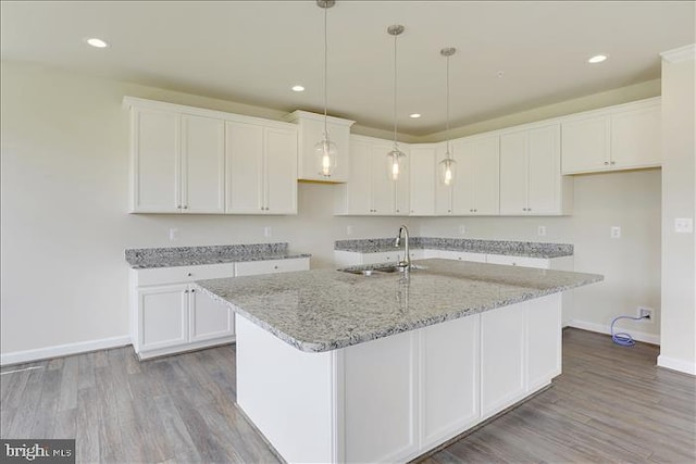 kitchen with white cabinets, a kitchen island with sink, and sink