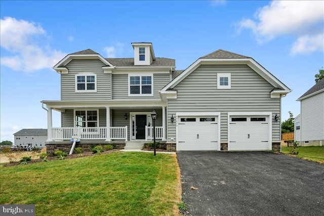 view of property featuring a porch, a garage, and a front lawn