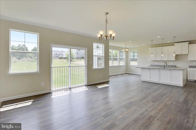 interior space with dark hardwood / wood-style flooring, a kitchen island with sink, a chandelier, white cabinetry, and hanging light fixtures