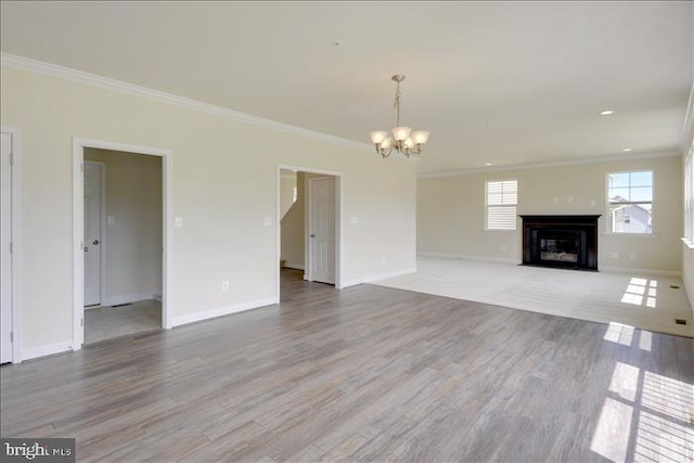 unfurnished living room featuring an inviting chandelier, wood-type flooring, and ornamental molding