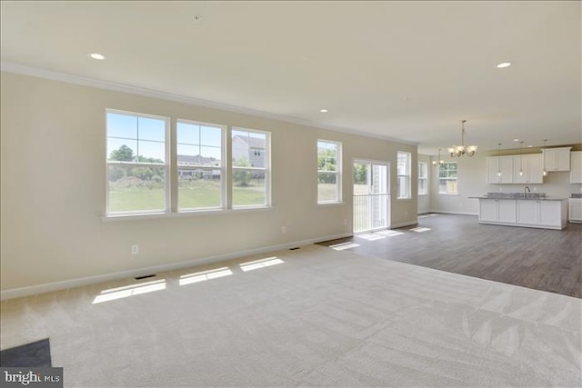 unfurnished living room featuring a chandelier, light carpet, and crown molding