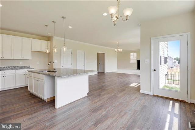 kitchen featuring white cabinetry, sink, an island with sink, and hanging light fixtures