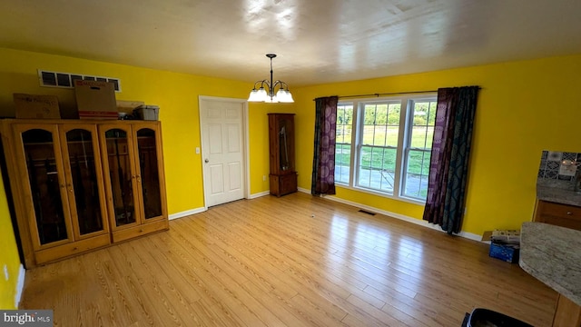 dining area with light wood-type flooring and a notable chandelier