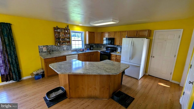 kitchen with decorative backsplash, a center island, black appliances, and light hardwood / wood-style flooring