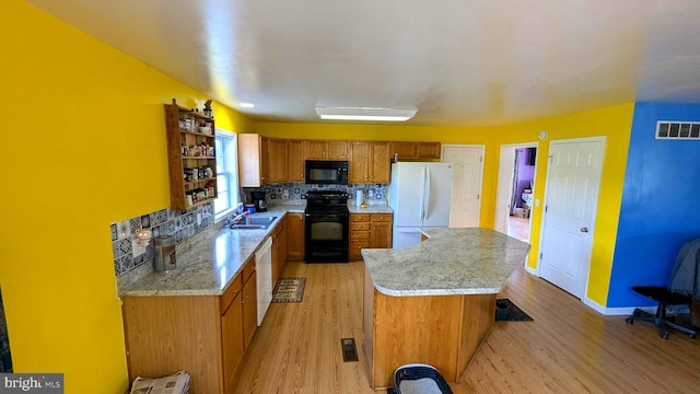 kitchen featuring sink, light wood-type flooring, backsplash, and black appliances