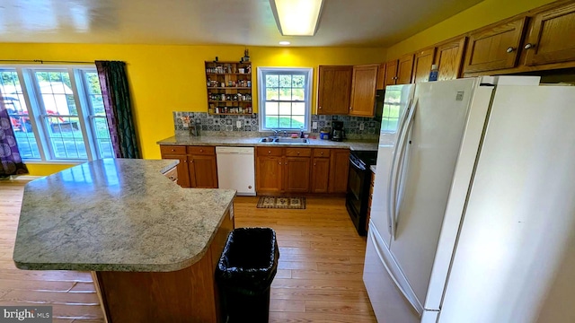 kitchen with tasteful backsplash, a wealth of natural light, white appliances, and light wood-type flooring