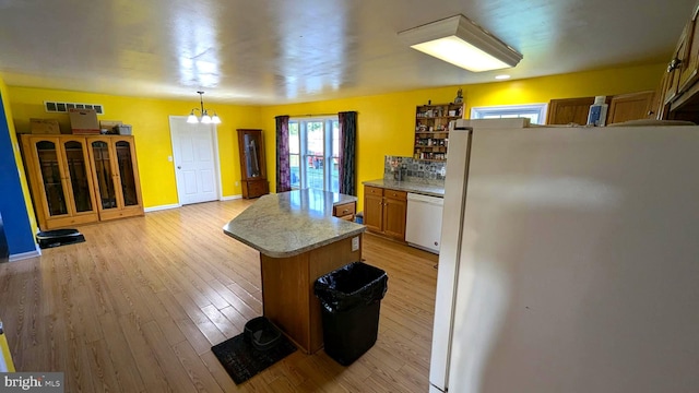 kitchen with refrigerator, pendant lighting, a notable chandelier, dishwasher, and a center island