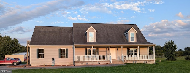 cape cod home with covered porch and a front yard