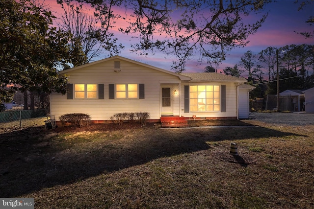 ranch-style home featuring a lawn and fence