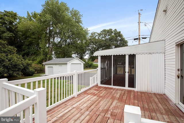 wooden terrace featuring a garage, a sunroom, a yard, and an outdoor structure