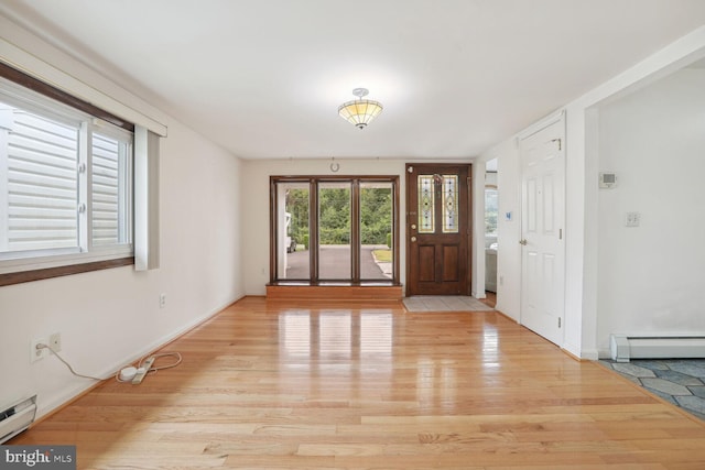 entrance foyer with baseboard heating, a wealth of natural light, and light hardwood / wood-style flooring