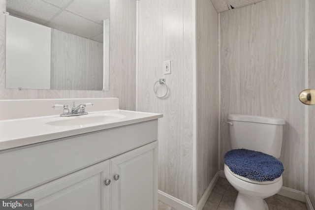 bathroom featuring toilet, tile patterned floors, a drop ceiling, and vanity