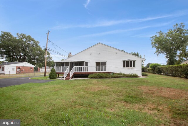 back of property with a sunroom and a yard