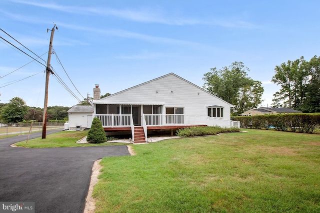 farmhouse-style home with a front lawn and a sunroom