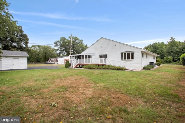 rear view of house with a yard, a sunroom, and central air condition unit