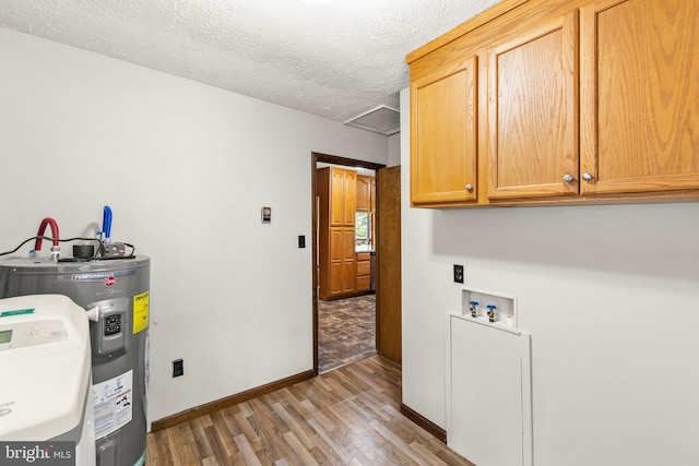 laundry area with washer / dryer, electric water heater, dark hardwood / wood-style floors, a textured ceiling, and cabinets