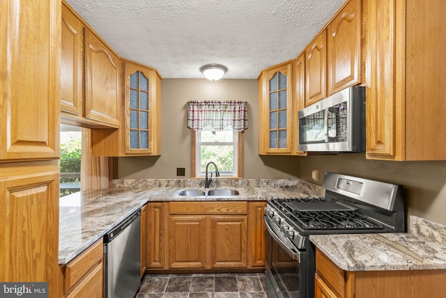 kitchen featuring light stone counters, sink, a textured ceiling, and appliances with stainless steel finishes