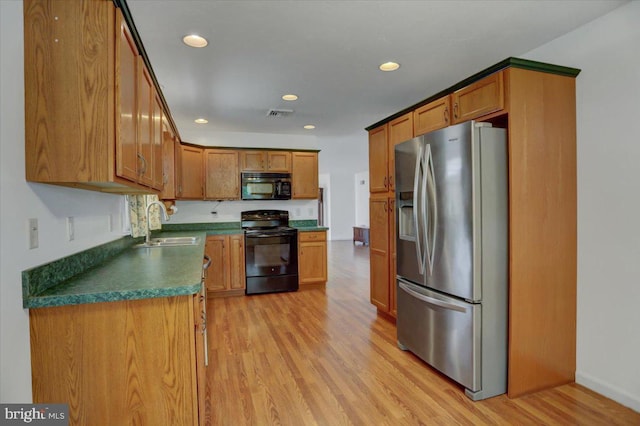 kitchen with sink, black appliances, and light hardwood / wood-style floors